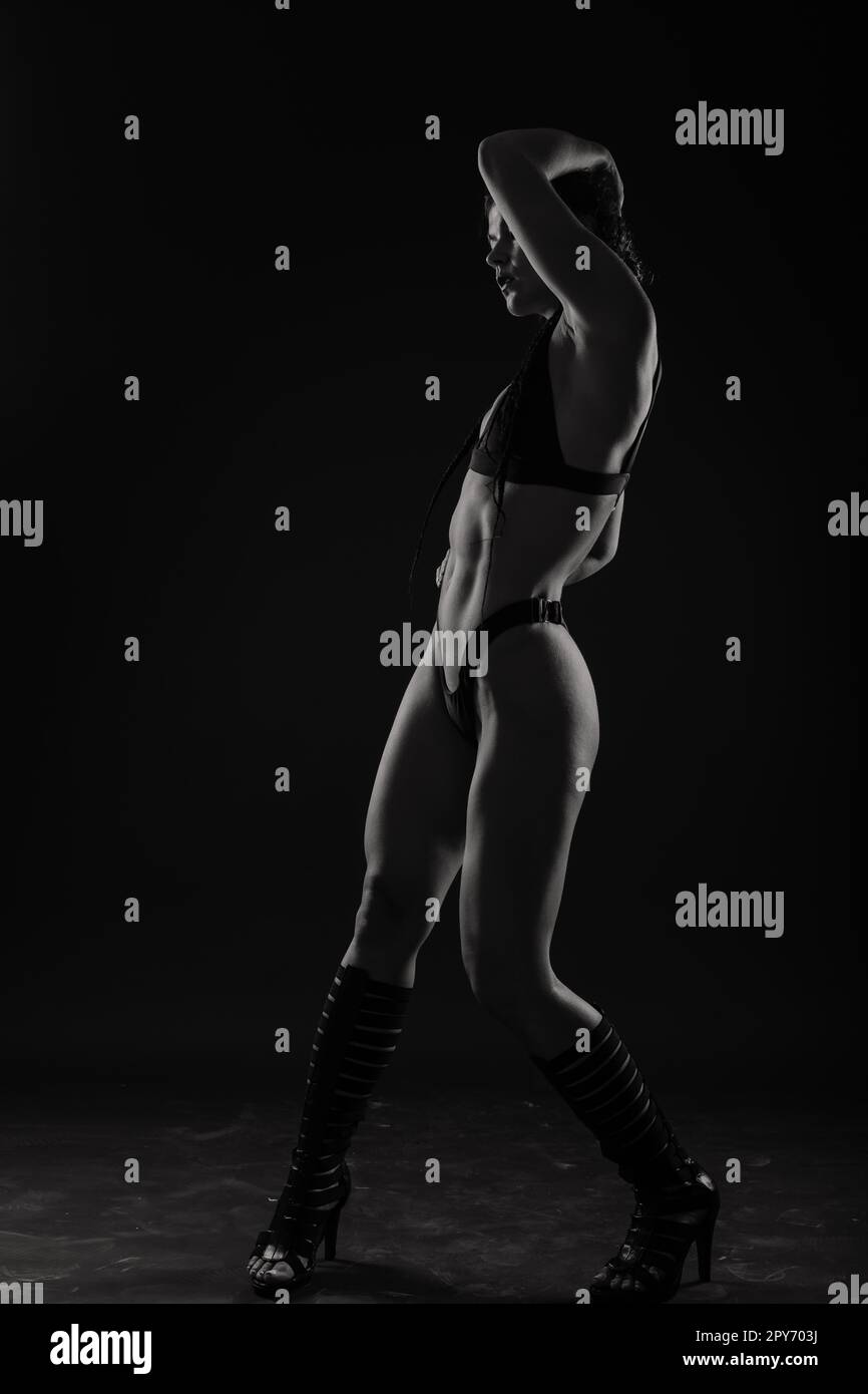 Femme sportive avec de grands muscles abdominaux dans des vêtements de sport noirs. Un corps de sport de près. Banque D'Images