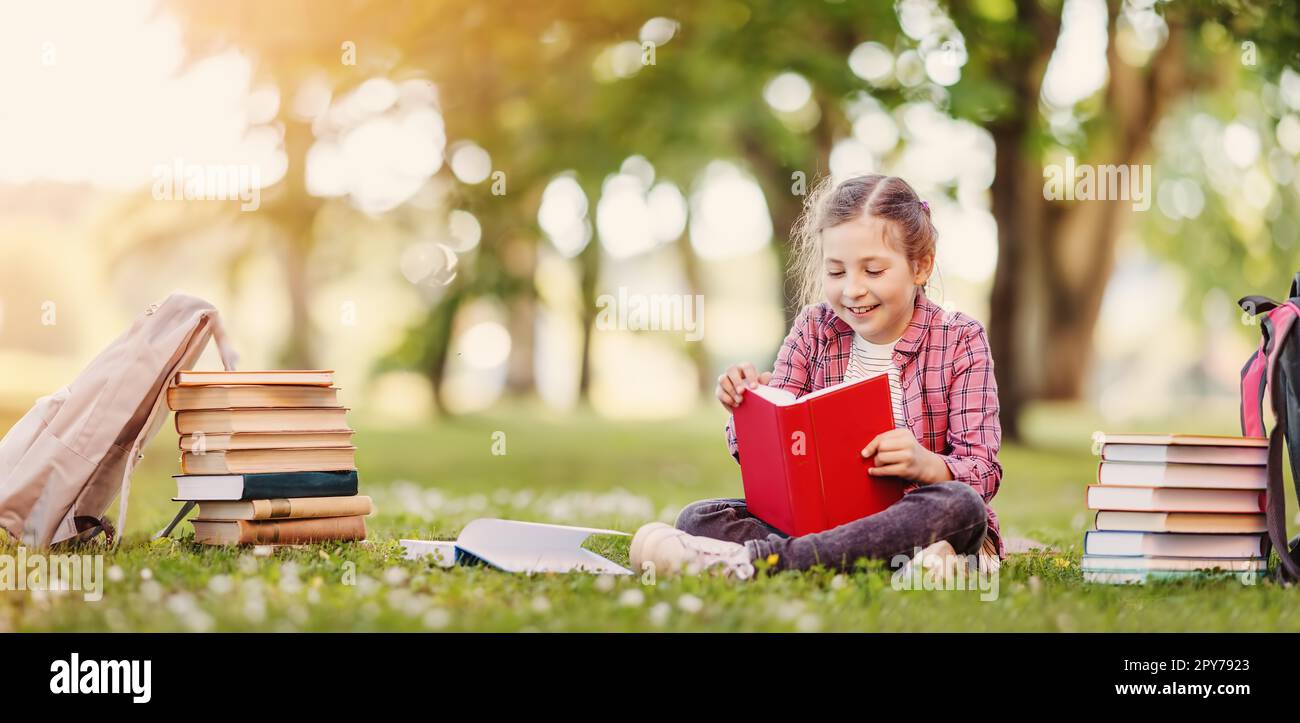 Fille de solitude assise sur la prairie verte et préparant un livre. Banque D'Images