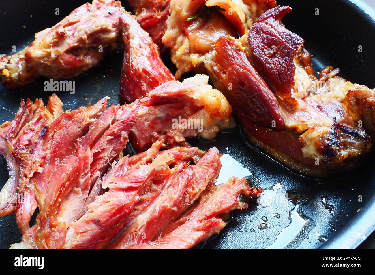 Épaule ou genou de porc fumé rôti. Délicieuse viande sur une plaque de cuisson noire avec des gouttes d'huile végétale, sortie du four. Spécialité de porc pour le dîner dans un restaurant et déjeuner en famille. Viande rouge Banque D'Images