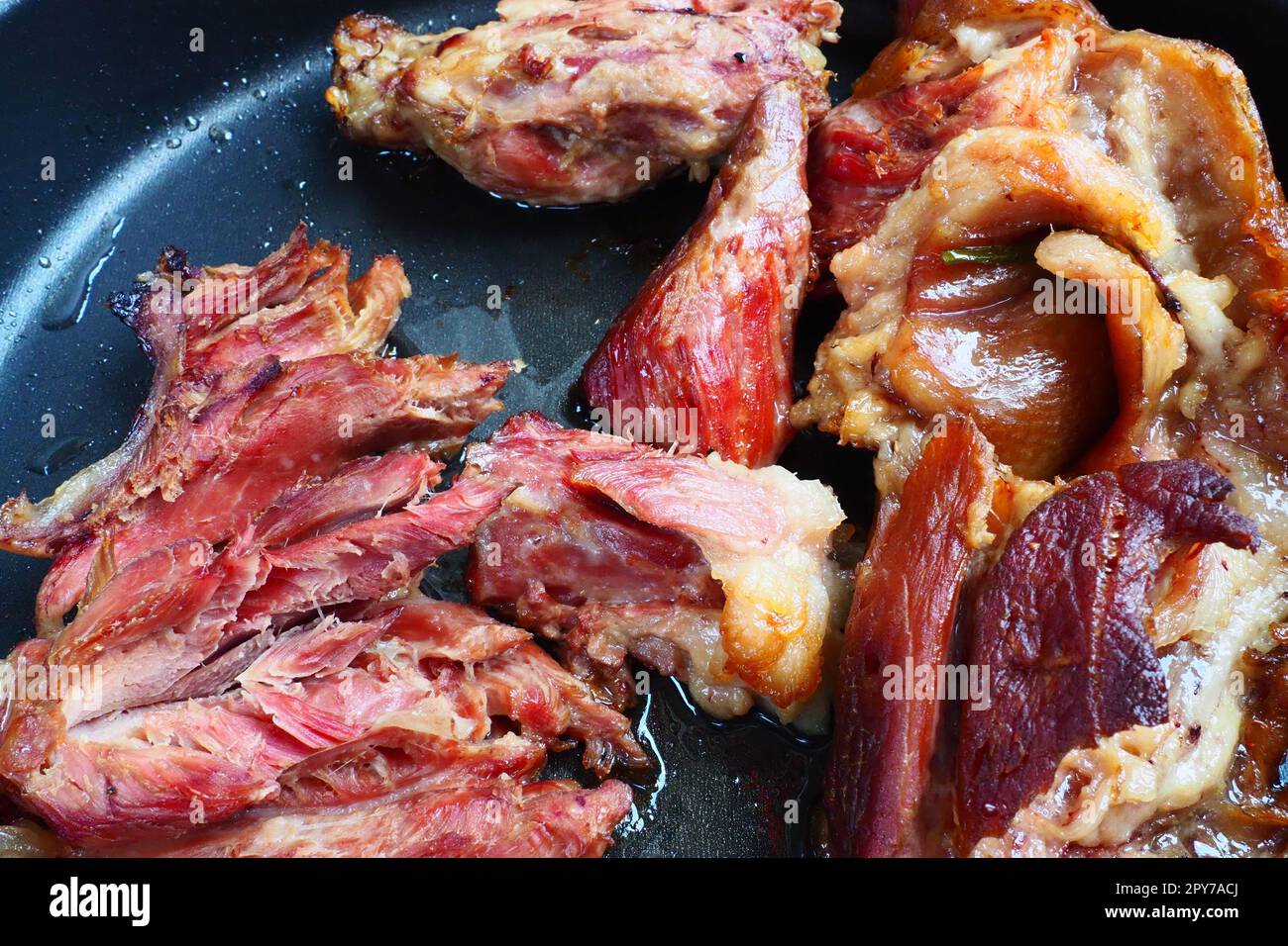 Épaule ou genou de porc fumé rôti. Délicieuse viande sur une plaque de cuisson noire avec des gouttes d'huile végétale, sortie du four. Spécialité de porc pour le dîner dans un restaurant et déjeuner en famille. Viande rouge Banque D'Images
