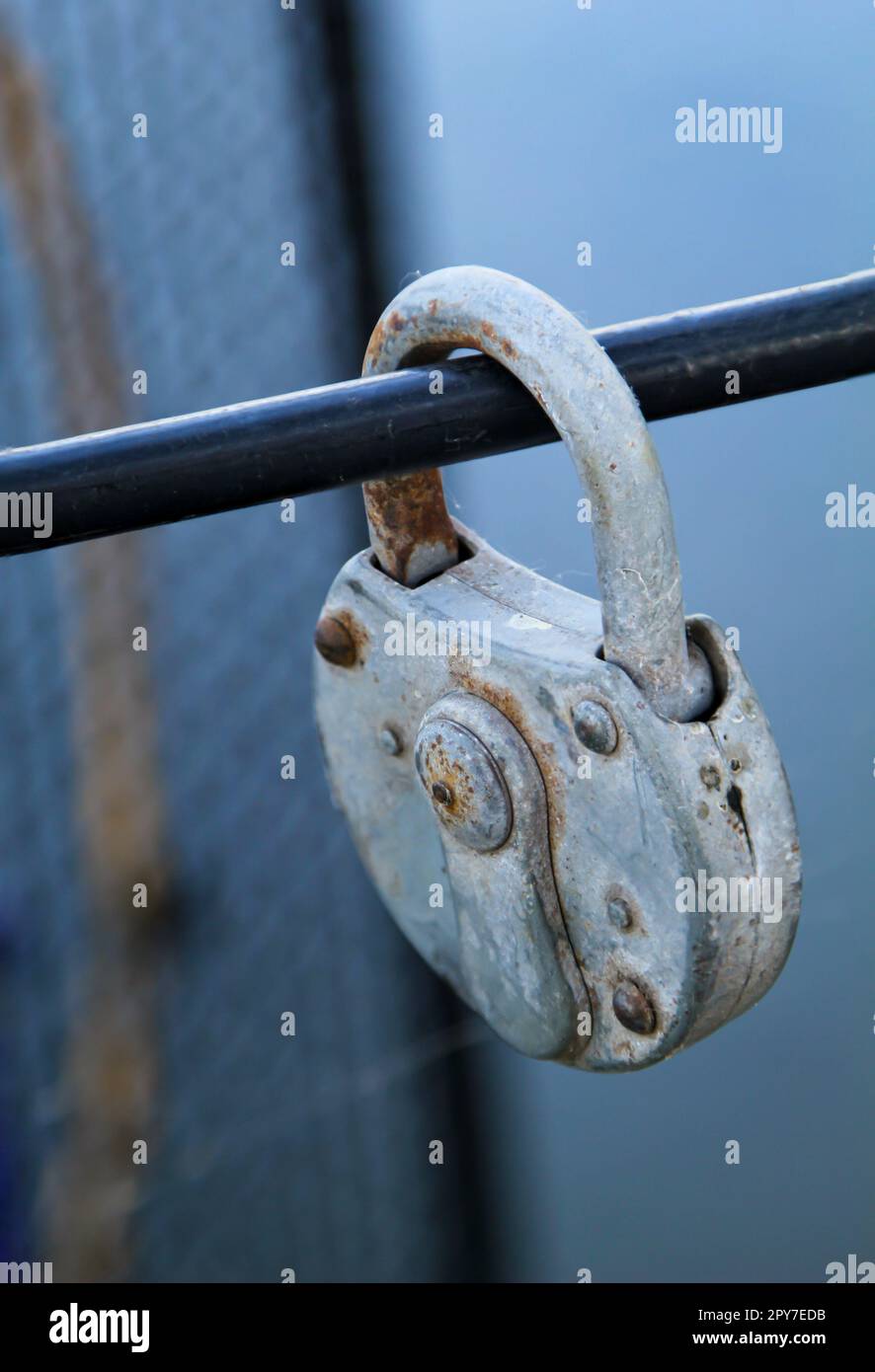 Un vieux cadenas, comme serrure d'amour, preuve d'amour attaché à une grille métallique. Banque D'Images