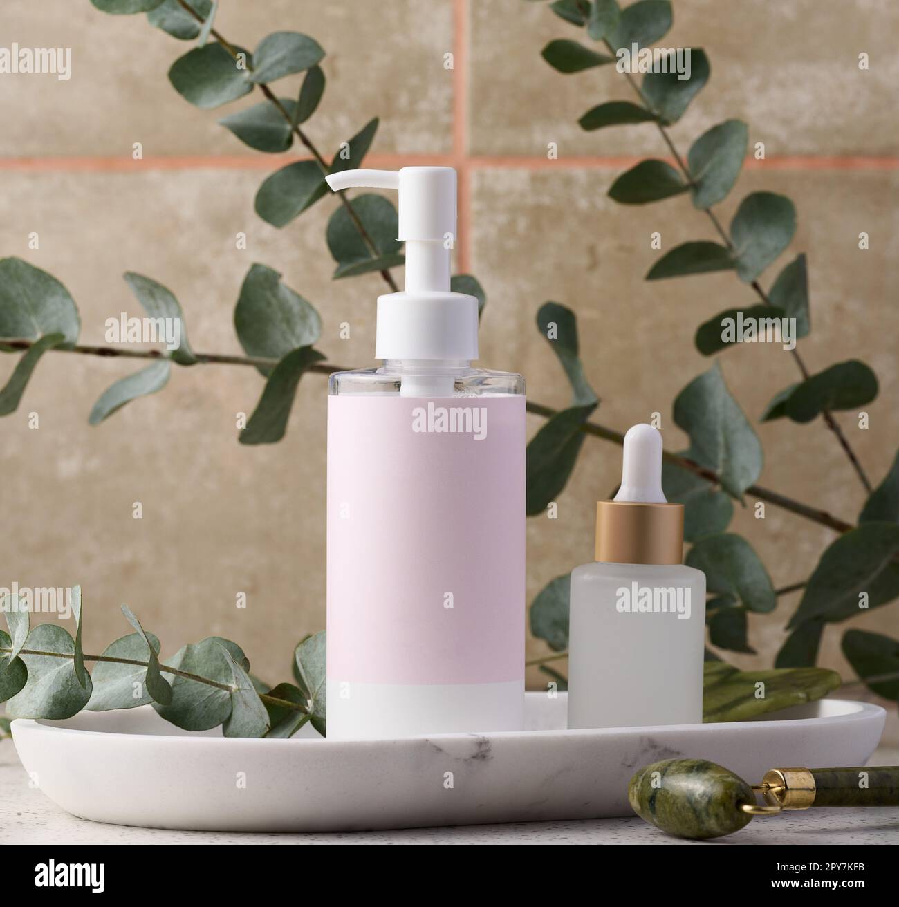 Bouteille en plastique avec distributeur et étiquette en papier vide sur un support en marbre, à côté d'une bouteille en verre avec compte-gouttes, produits cosmétiques Banque D'Images