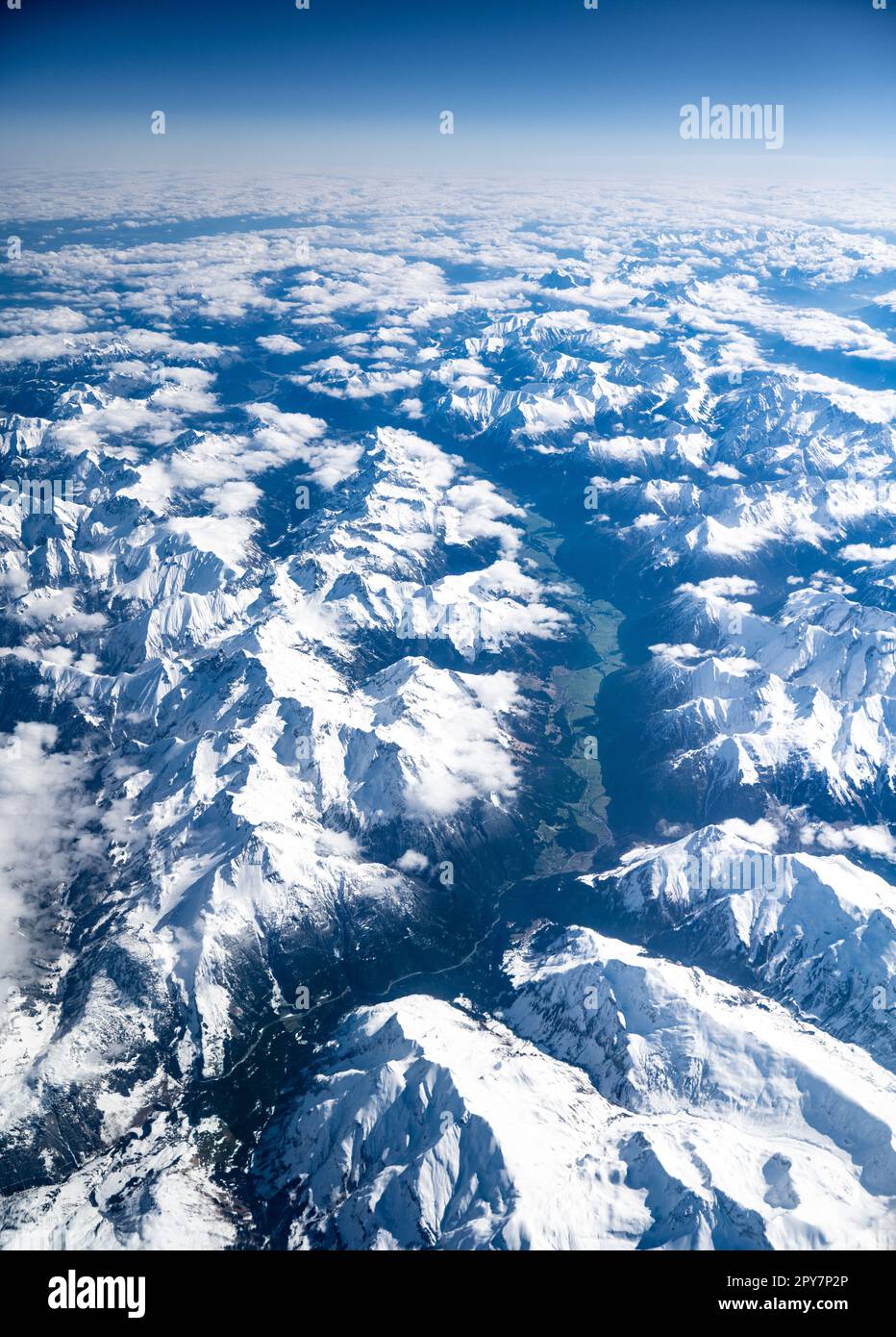 Vue sur une journée ensoleillée sans nuages depuis l'avion sur les Alpes autrichiennes dont les sommets sont encore couverts de neige et les vallées sont vertes. Banque D'Images