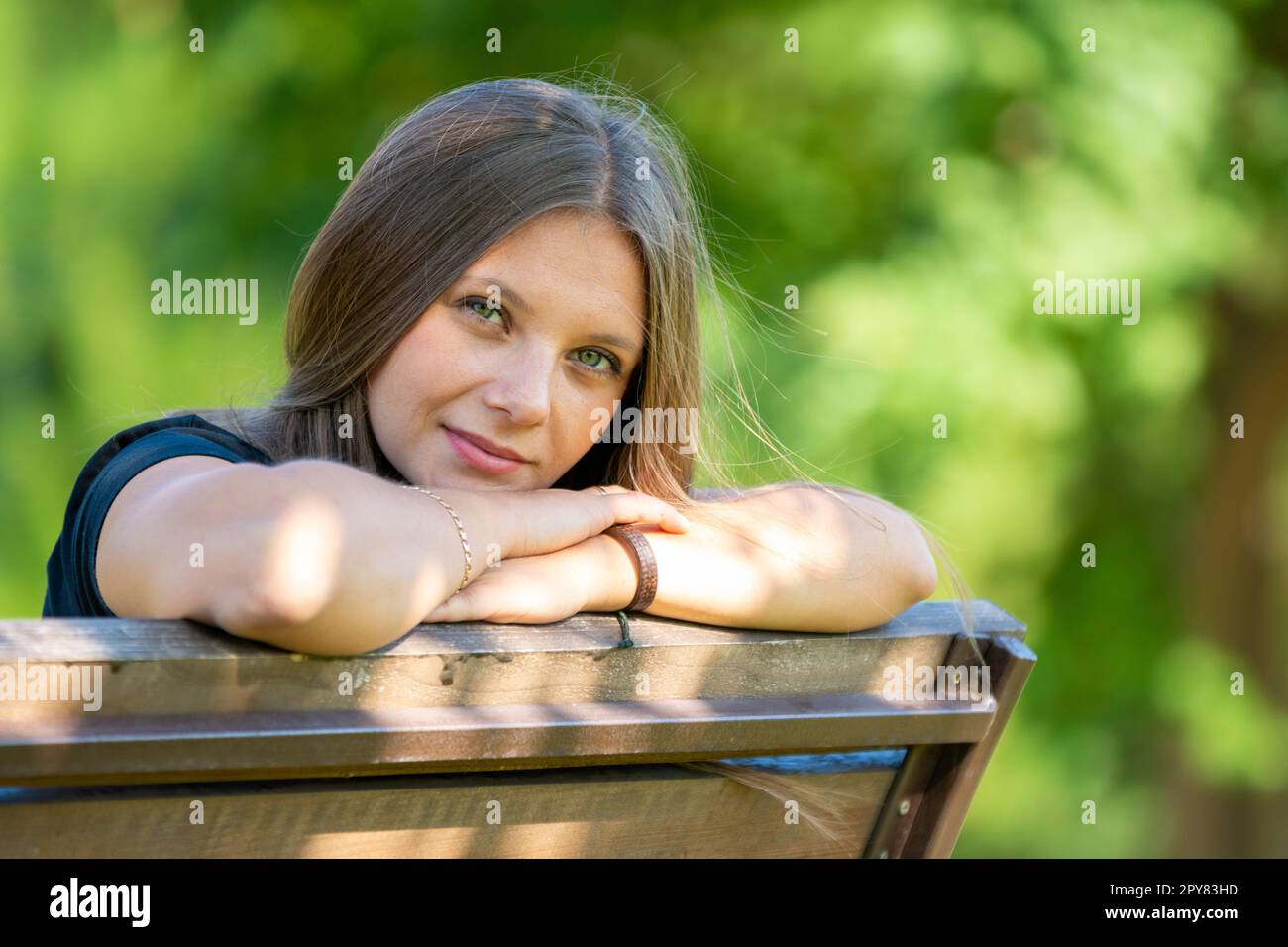 Portrait d'une belle fille assise sur un banc et regardant heureusement dans le cadre Banque D'Images