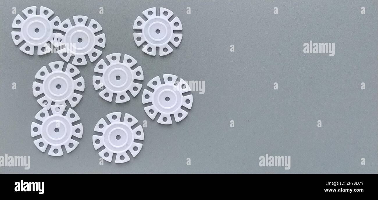 Détails blancs en forme de flocons de neige du designer pour enfants sur fond gris dans la partie gauche de l'image. Disques en plastique pour le développement de la motricité fine Banque D'Images