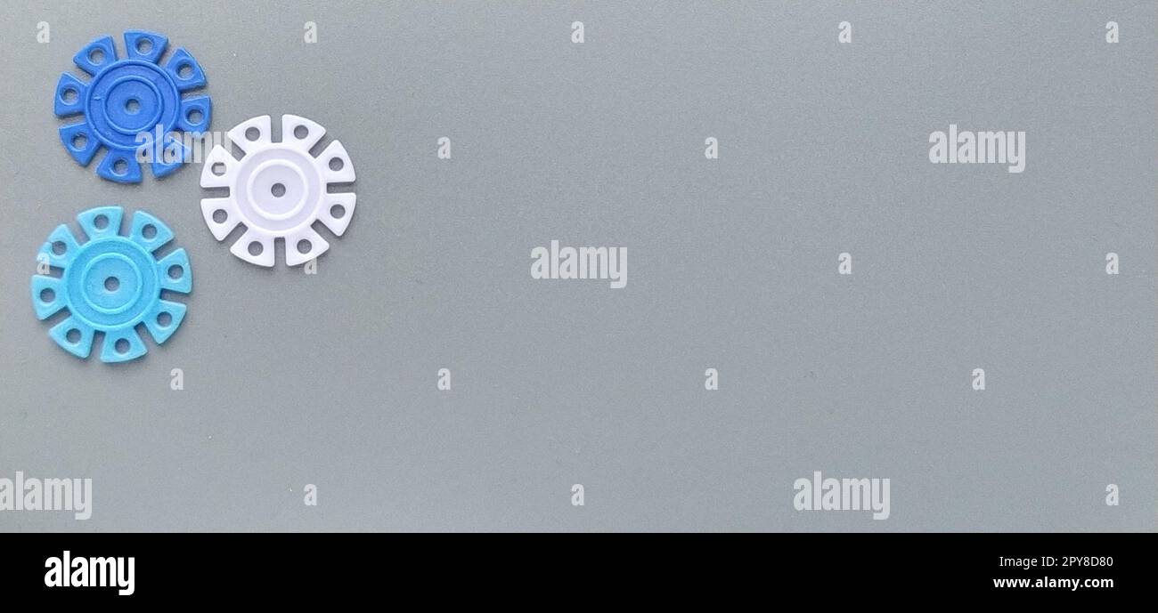 Détails multicolores en forme de flocons de neige du designer pour enfants sur fond gris. Disques en plastique blanc, bleu clair et bleu marine pour le développement de la motricité fine des doigts Banque D'Images