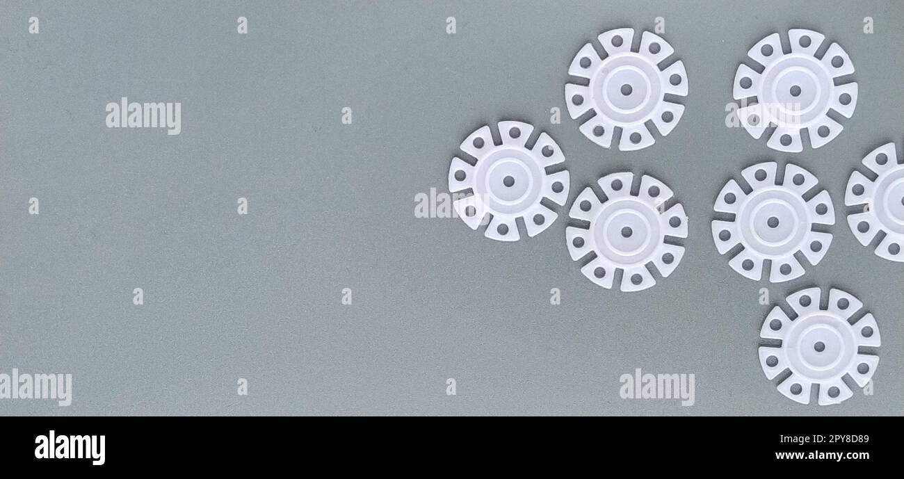 Détails blancs en forme de flocons de neige du designer pour enfants sur fond gris dans la partie gauche de l'image. Disques en plastique pour le développement de la motricité fine Banque D'Images