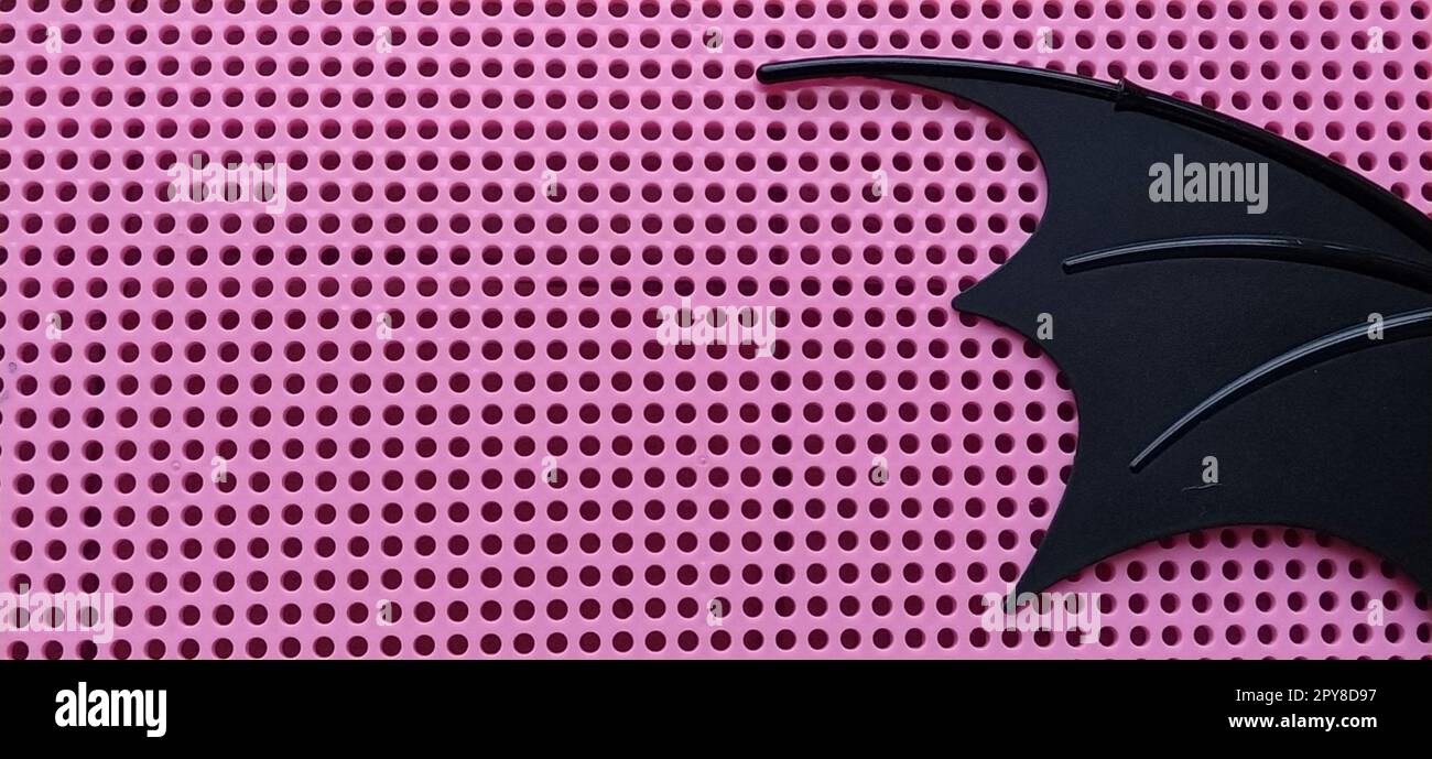 Aile de chauve-souris noire en plastique. Panneau rose avec trous pour mosaïque. Détails des jouets pour enfants. Banque D'Images
