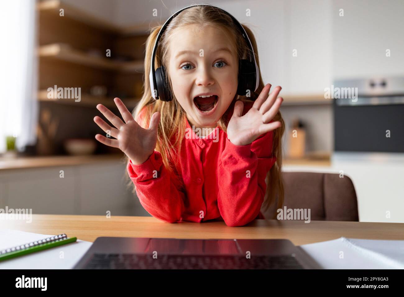 Génial. POV de la petite fille excitée dans le casque en utilisant l'ordinateur portable à la maison Banque D'Images