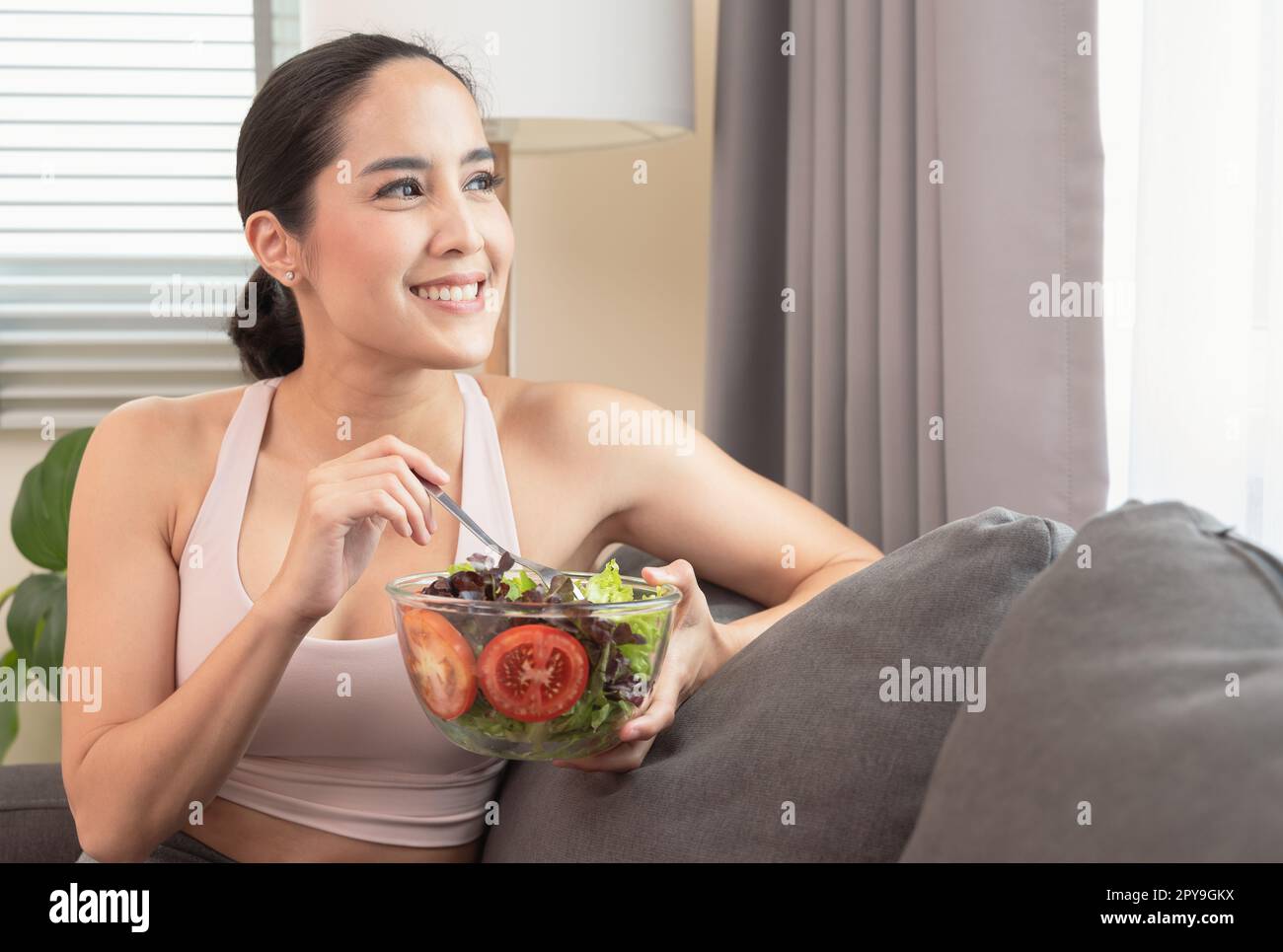 Femme souriante ayant un petit déjeuner sain à la maison après l'entraînement de yoga avec bonheur. Banque D'Images