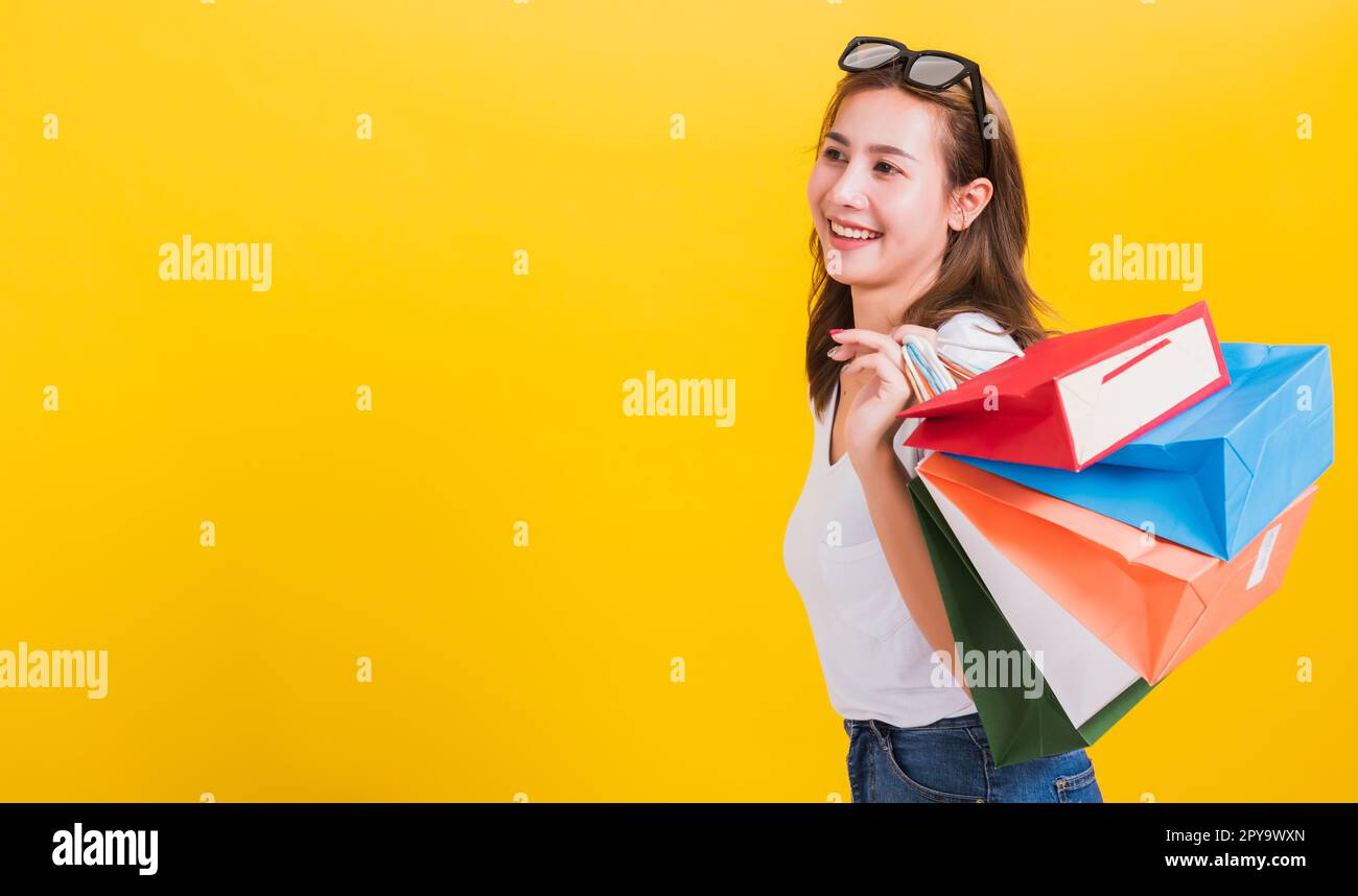 femme adolescente souriante debout avec des lunettes de soleil excitée tenant des sacs de shopping multicolore Banque D'Images