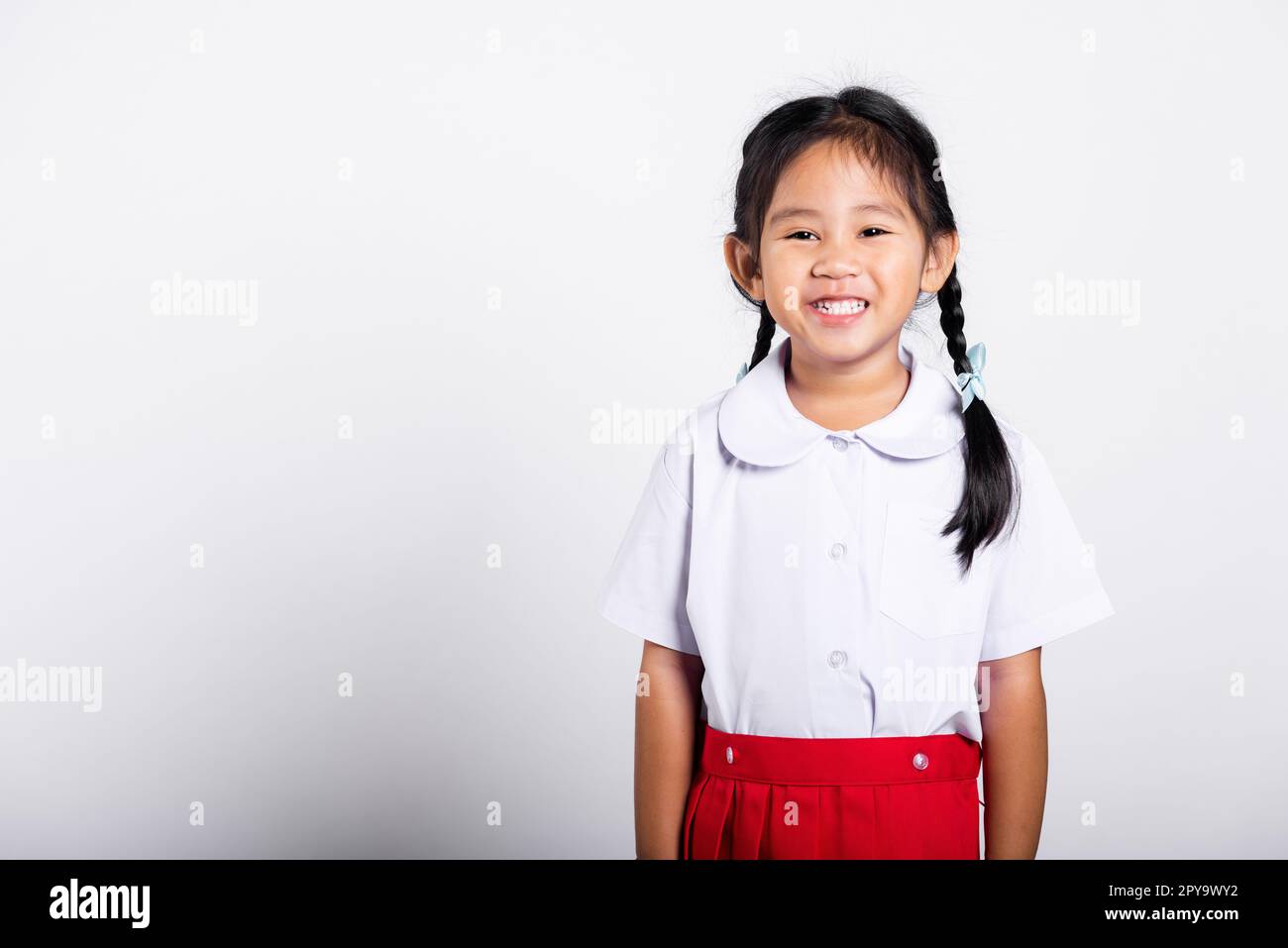 Asiatique adorable tout-petit souriant heureux portant l'uniforme thaï étudiant debout Banque D'Images