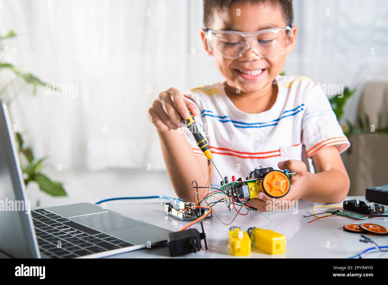 Enfant asiatique assemblant le projet de travail de robot de voiture Arduino à la maison Banque D'Images