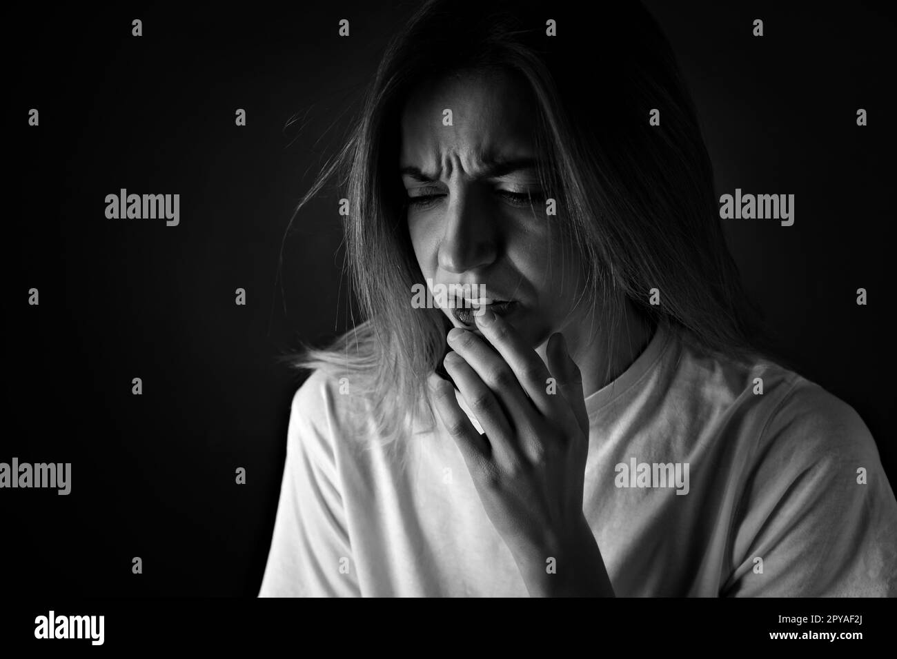 Femme atteinte du visage sur fond noir, espace pour le texte. Victime de violence domestique Banque D'Images