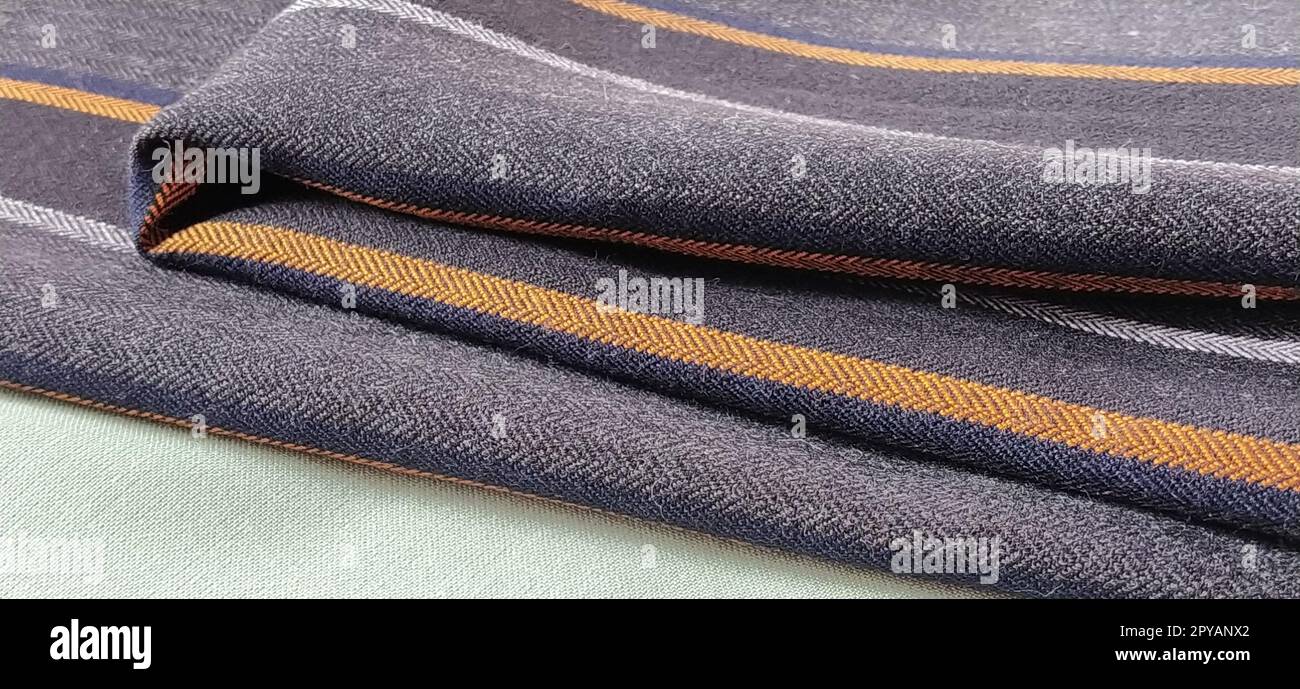 Tissu plié vert clair et noir-gris avec rayures orange et bleu foncé. Décoration intérieure. Habiller les tissus dans un style décontracté. Matériau dense pour rideaux d'intérieur et finition de meubles Banque D'Images