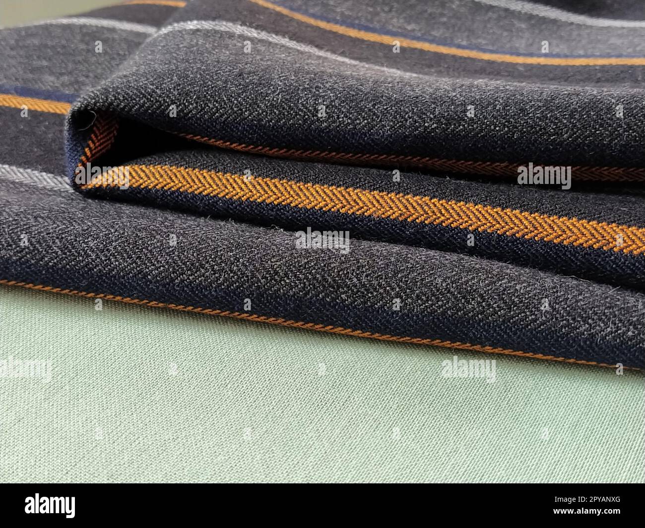 Tissu plié vert clair et noir-gris avec rayures orange et bleu foncé. Décoration intérieure. Habiller les tissus dans un style décontracté. Matériau dense pour rideaux d'intérieur et finition de meubles Banque D'Images