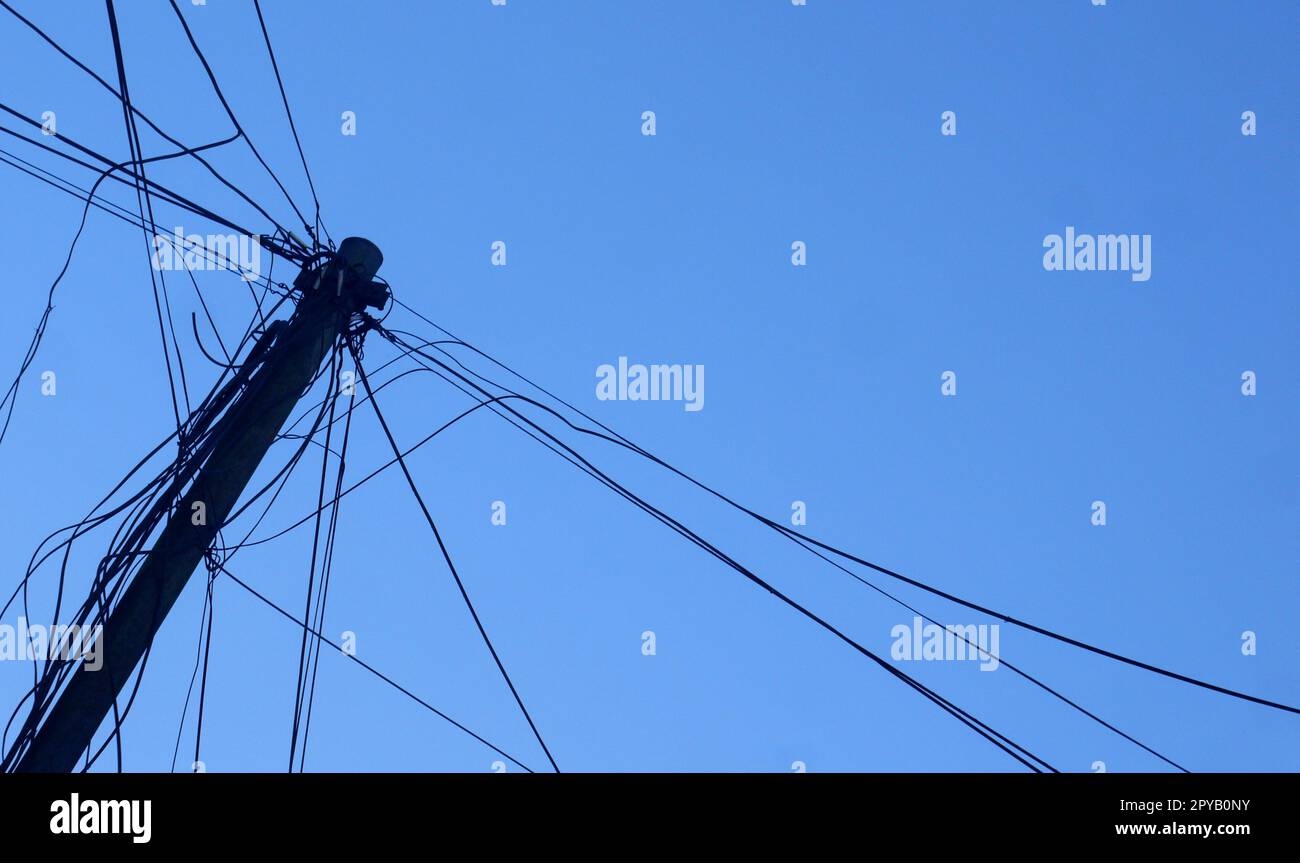 poteaux électriques avec câbles noirs désordonnés sur fond bleu ciel Banque D'Images