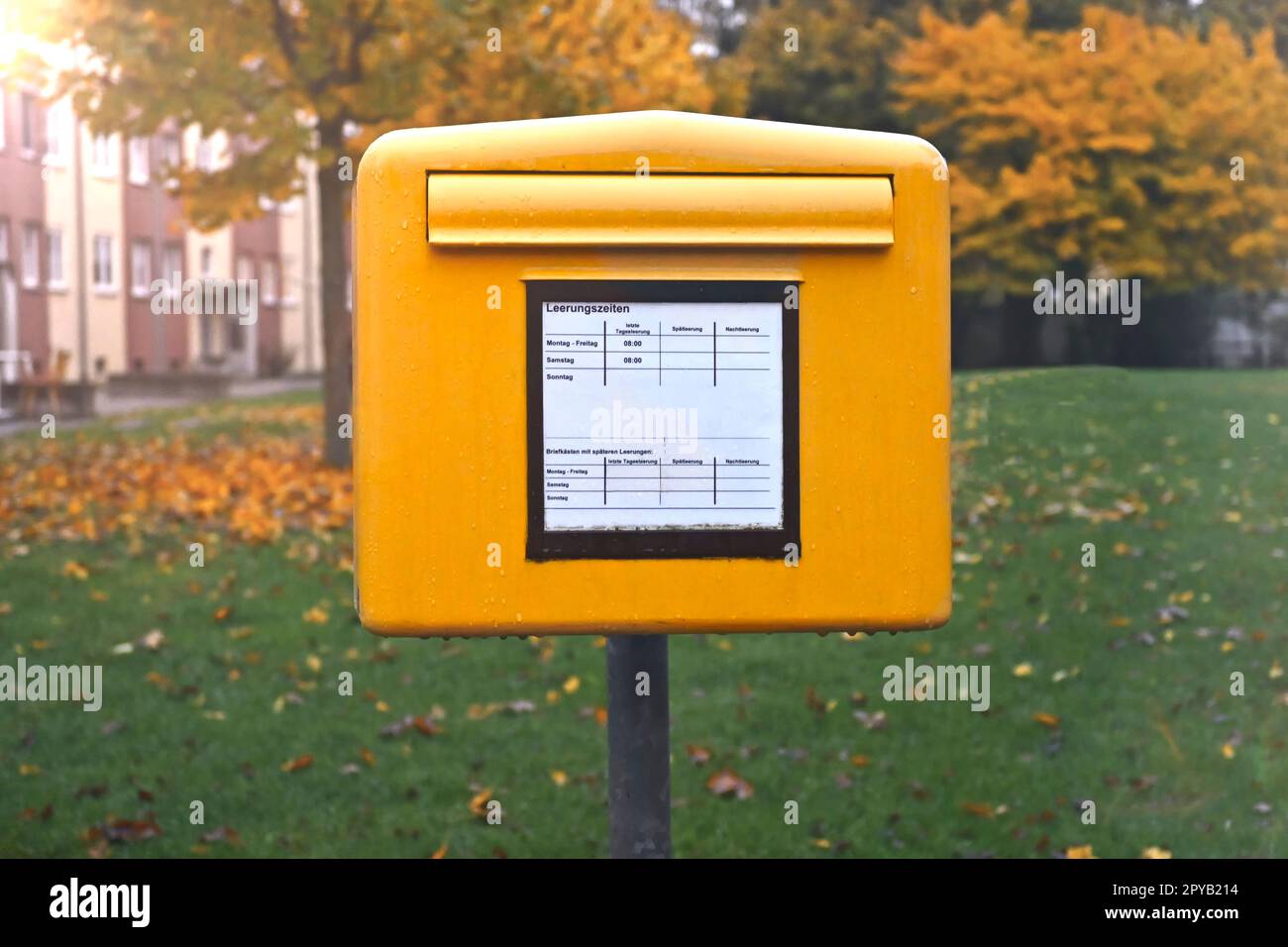 Vieille boîte aux lettres jaune devant un paysage d'automne. Banque D'Images