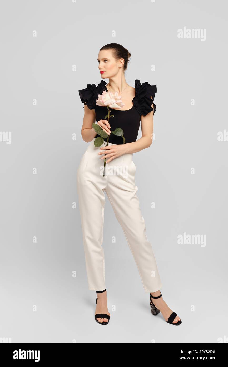Femme élégante posant dans un studio blanc avec fleur dans les mains Banque D'Images