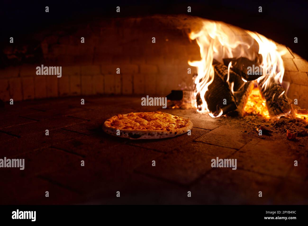 La pizza est cuite dans un four à bois traditionnel avec cheminée Banque D'Images