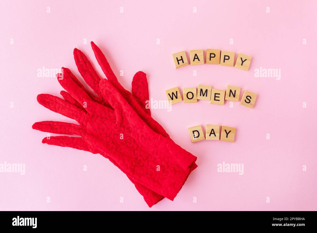 Beaux gants en dentelle rouge sur lesquels des cubes en bois avec l'inscription Happy Women's day. Carte prête pour les vacances, Journée de la femme. Banque D'Images