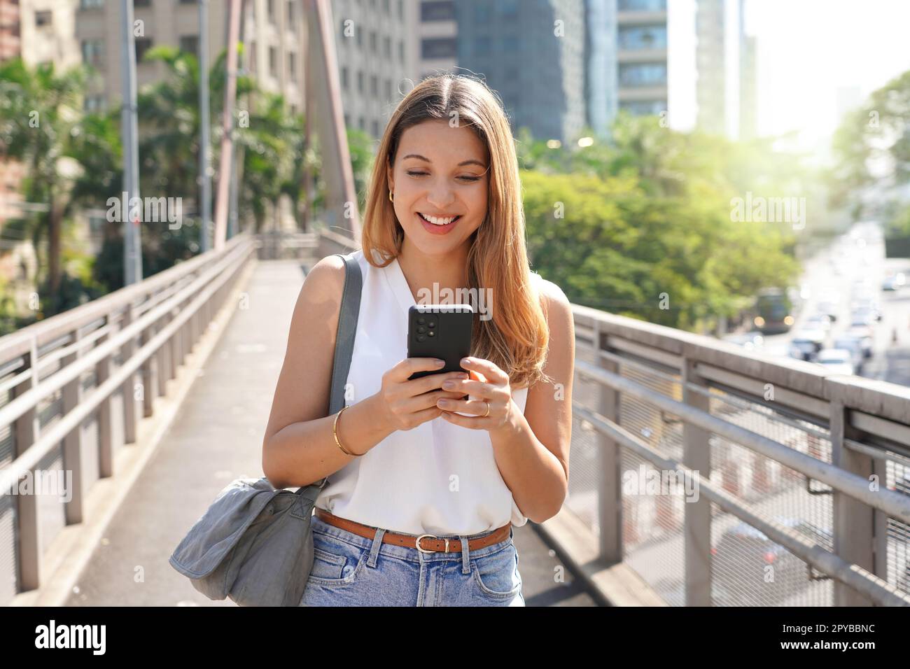 Entrepreneur caucasien brésilien marchant dans le centre-ville de Sao Paulo messagerie avec un téléphone cellulaire Banque D'Images