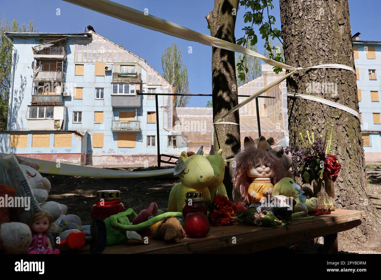 Un mémorial spontané avec des jouets pour enfants dédiés aux victimes de  l'attaque à la roquette russe est vu par le bâtiment préservé pour la  reconstruction qui a été lourdement endommagé par