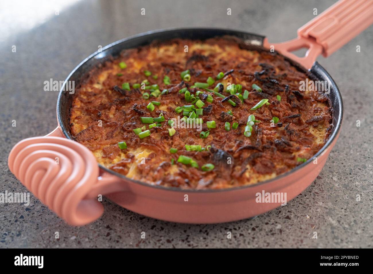 Poêle à frire en fonte rose avec fromage et oignons verts. Prise de vue large. Banque D'Images