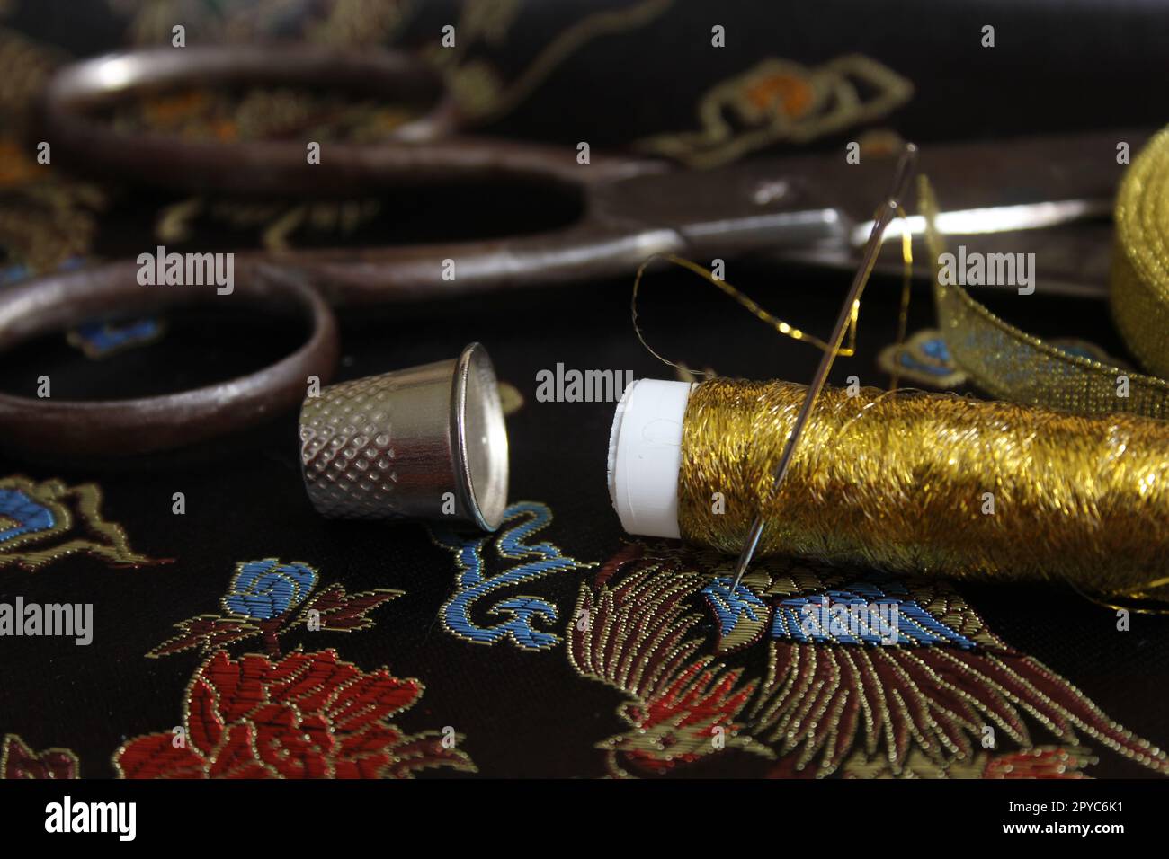 Bobine de fil d'or avec Thimble sur tissu de soie noir Vintage Banque D'Images