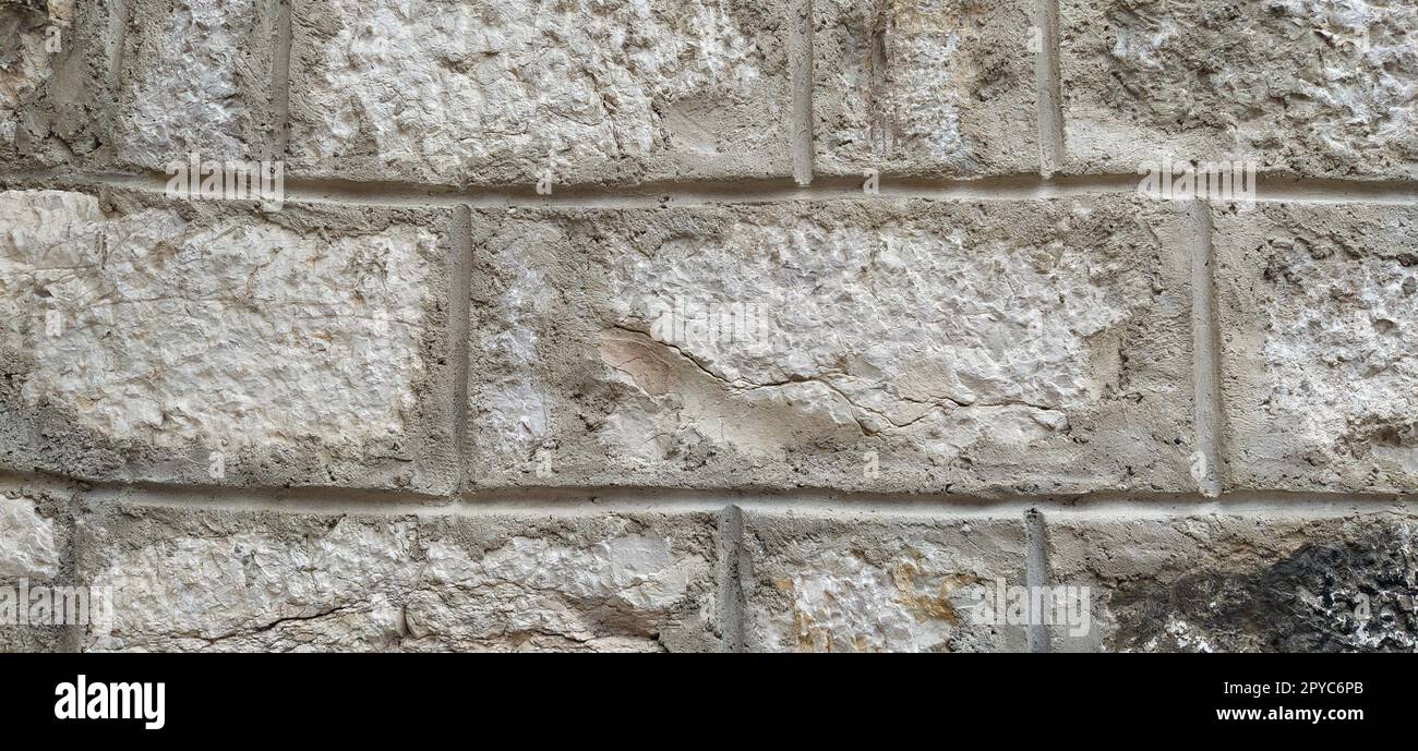 Maçonnerie en pierre vieillie patinée de la vieille maison. Ancien fond de mur de brique. Vieille texture de briques de pierre rayée inégale. Mur de bâtiment turc. Toile de fond de mur de calcaire rugueux Banque D'Images