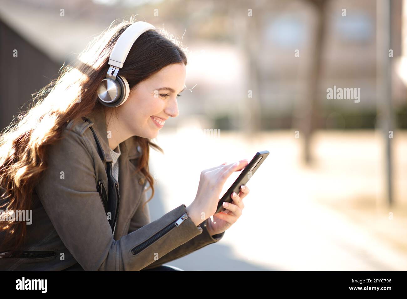 Femme heureuse écoutant l'audio sur le téléphone dans un parc Banque D'Images