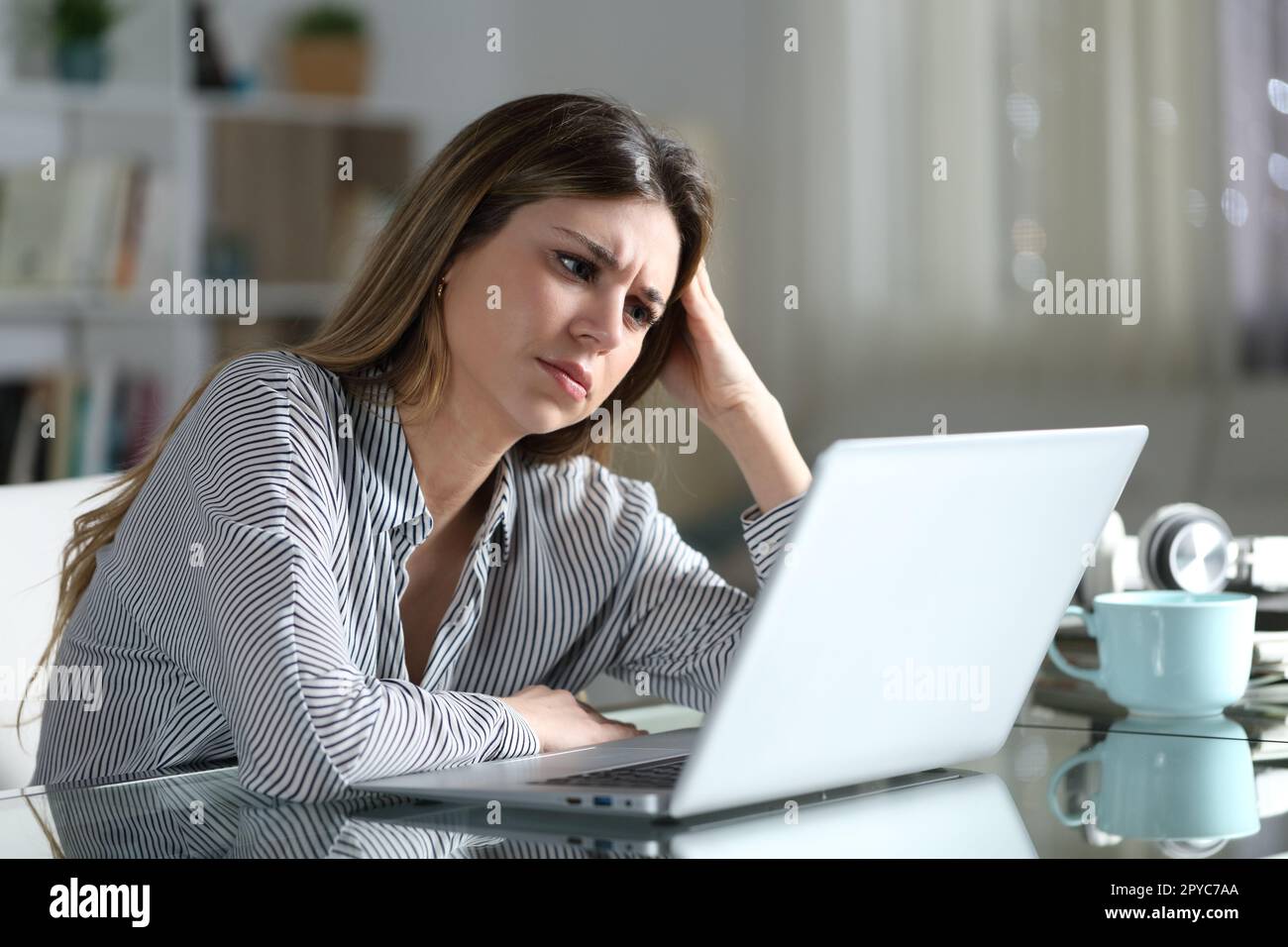 La femme inquiète vérifie le contenu de l'ordinateur portable à la maison Banque D'Images