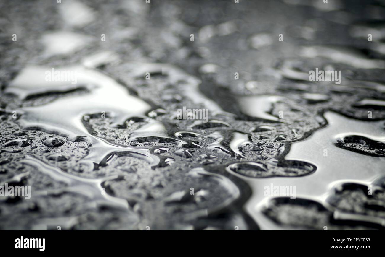 Gros plan des gouttes d'eau sur la surface argentée. Image horizontale avec mise au point sélective. Banque D'Images