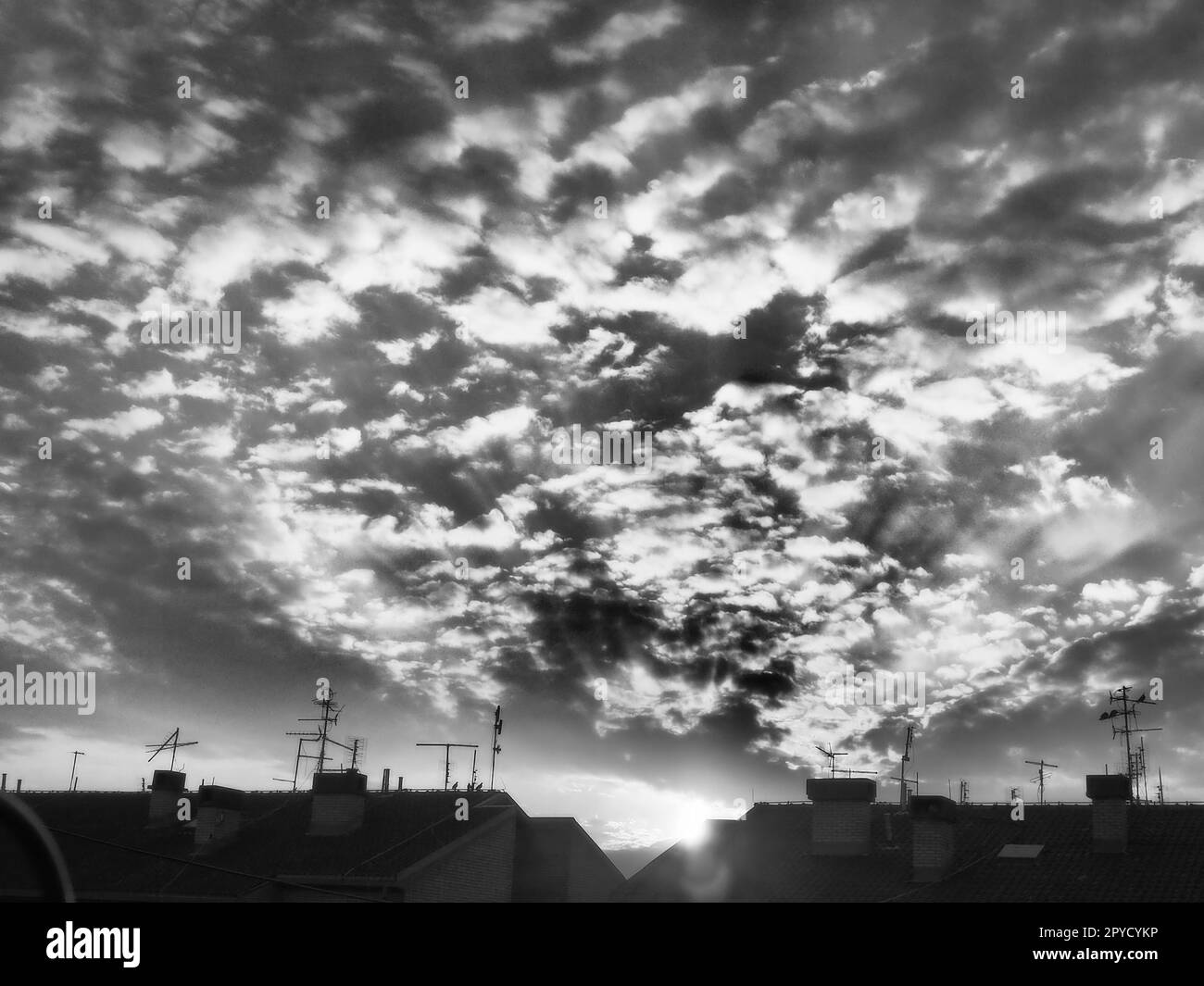 Coucher de soleil ou lever du soleil. Nuages dans le ciel du soir ou du matin. Les rayons du soleil transpercent les nuages. Photographie monochrome noir et blanc dans un style rétro ou vintage. Augmentation du niveau de bruit photo comme astuce artistique Banque D'Images