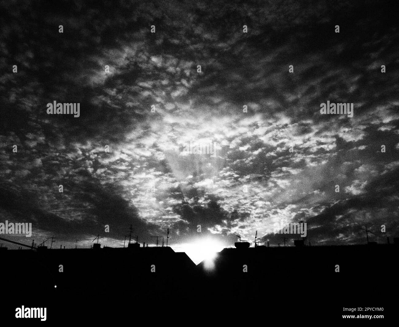 Coucher de soleil ou lever du soleil. Nuages dans le ciel du soir ou du matin. Les rayons du soleil transpercent les nuages. Photographie monochrome noir et blanc dans un style rétro ou vintage. Augmentation du niveau de bruit photo comme astuce artistique Banque D'Images