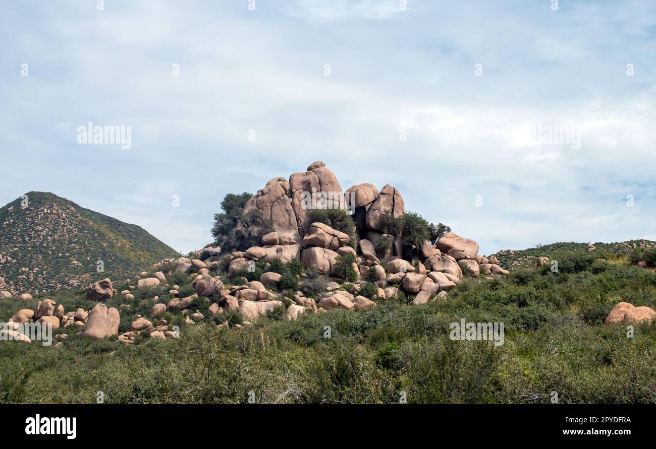 Les merveilles de la nature représentées dans un grand tas de rochers de formes et de tailles diverses sur le flanc d'une chaîne de montagnes. Le ciel bleu complète le vert Banque D'Images