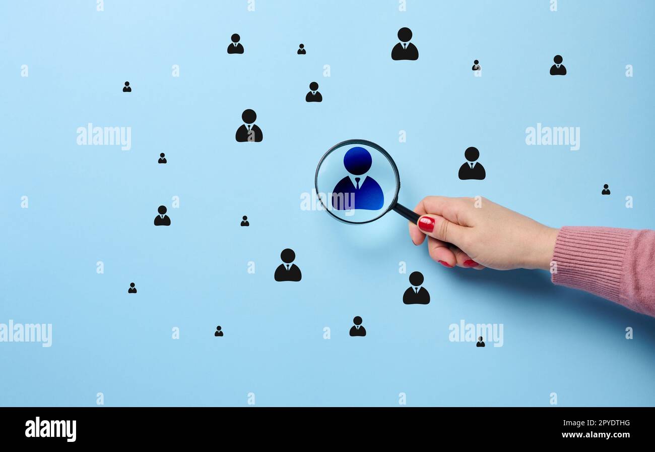 La main d'une femme tient une loupe et se concentre sur un badge de leadership, le concept de gestion des ressources humaines Banque D'Images