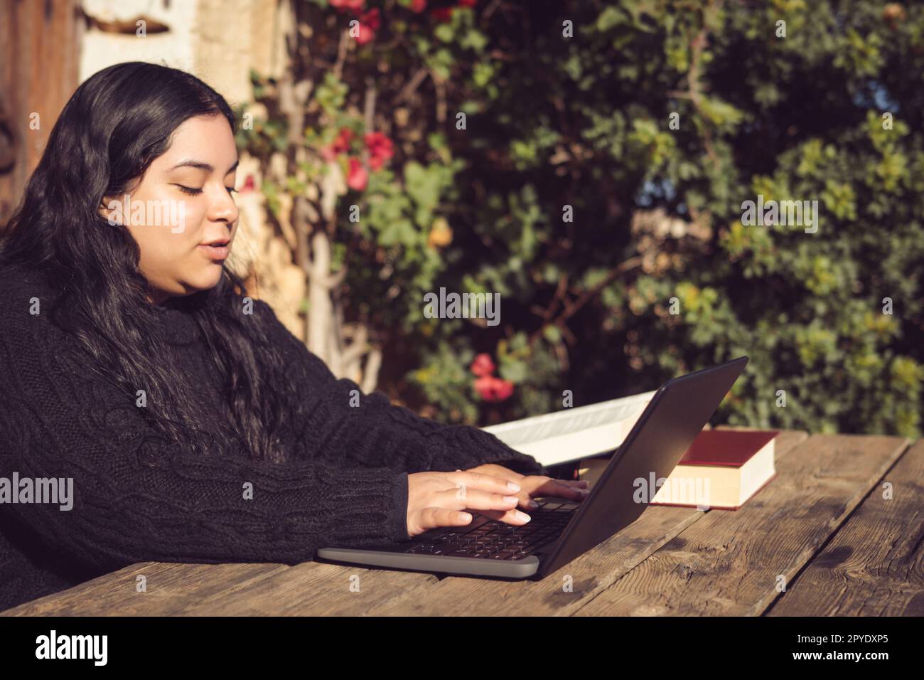 femme latine avec de longs cheveux foncés, travaillant à l'extérieur avec un ordinateur portable Banque D'Images