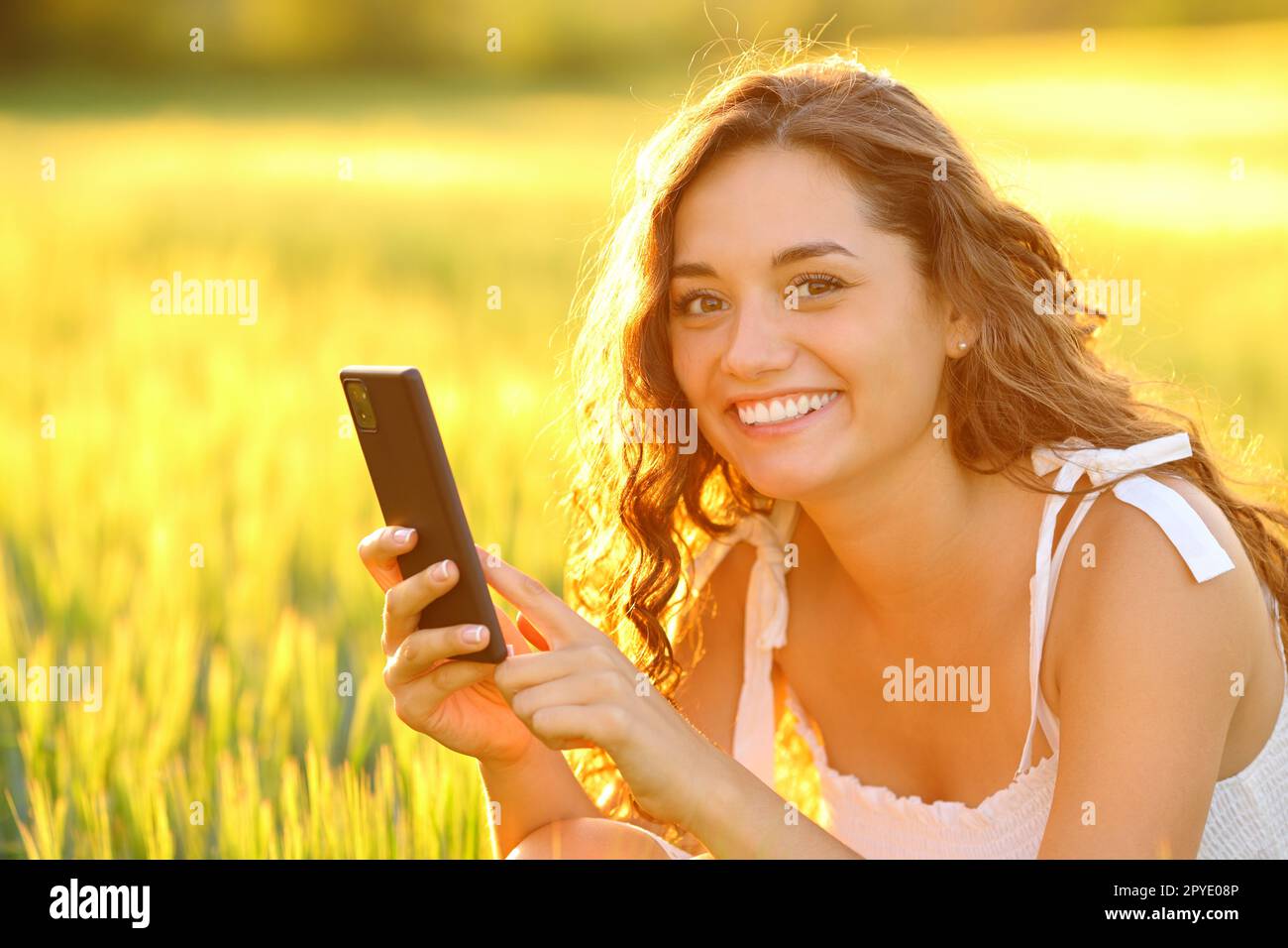 Femme heureuse posant dans un champ tenant le téléphone Banque D'Images