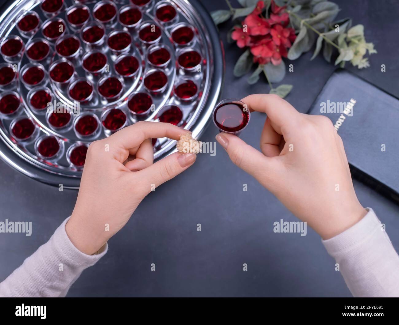 Gros plan de jeune femme prenant communion de petites tasses sur fond noir Banque D'Images