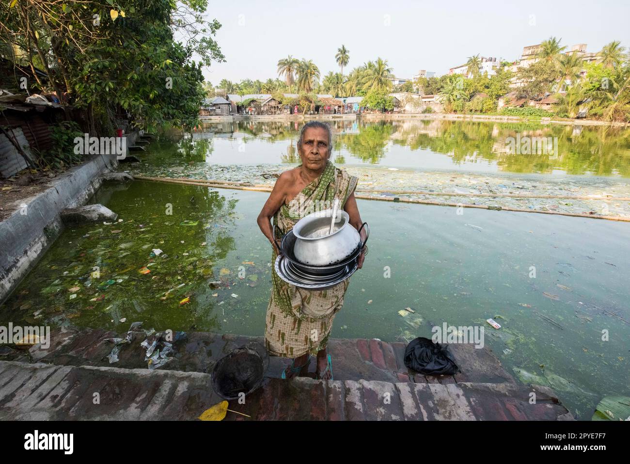 Bangladesh, Khulna, Sonadanga.A femme nettoie ses pots dans l'eau polluée de l'étang près de sa maison. 19 mars 2017. Usage éditorial uniquement. Banque D'Images