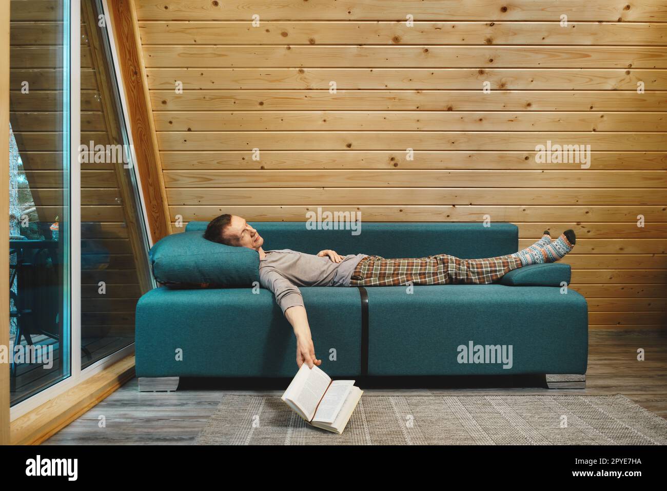 L'homme lisait un livre dans sa cabine en bois le jour des pluies et s'endormit Banque D'Images