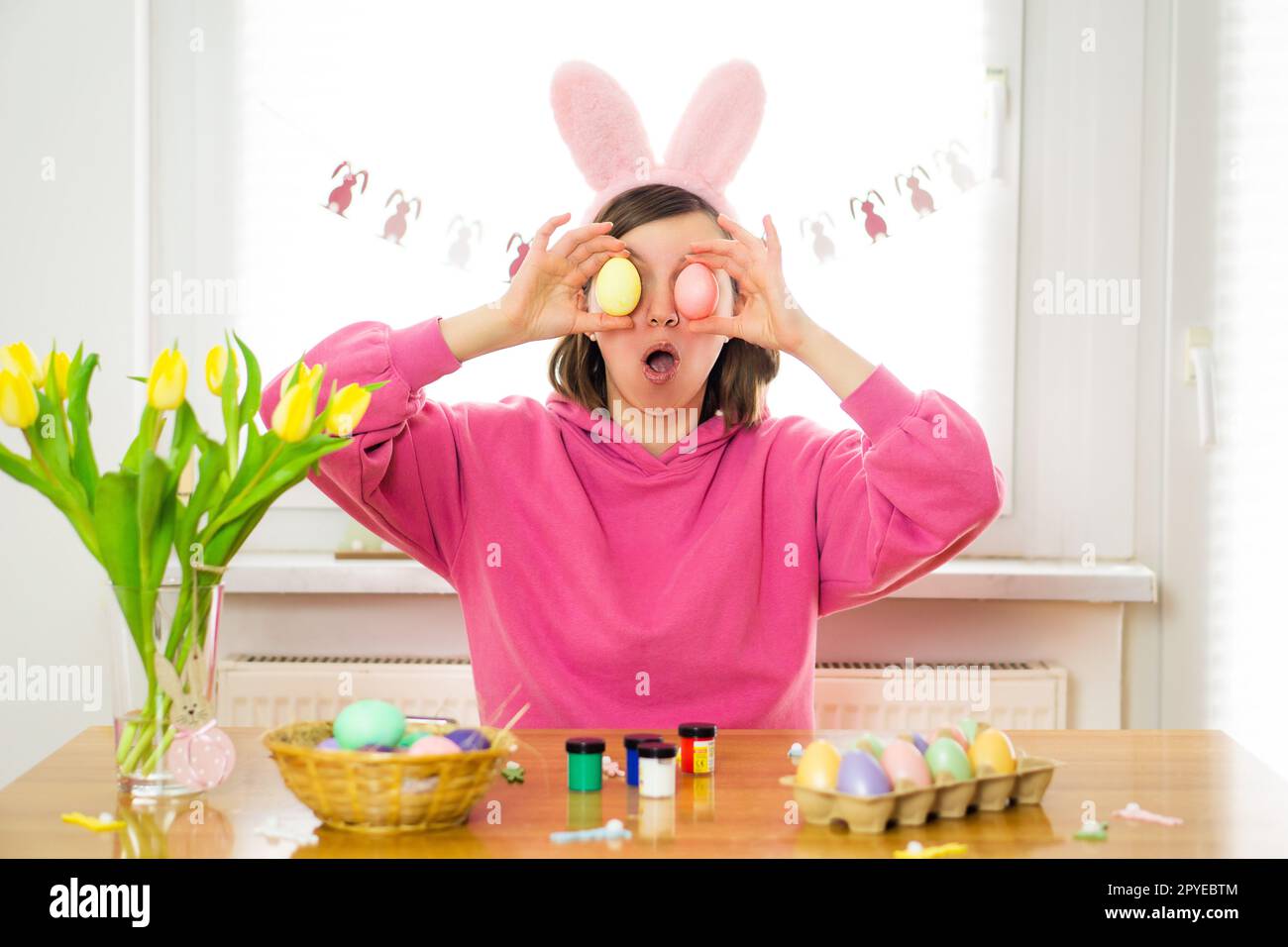 Jeune femme portant des oreilles de lapin s'amusant tout en peignant des œufs de Pâques à la maison. Préparation pour Pâques Banque D'Images