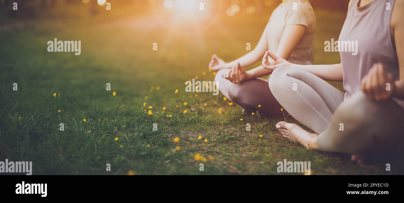 Deux femmes assises en tenue active en position lotus dans la nature. Banque D'Images