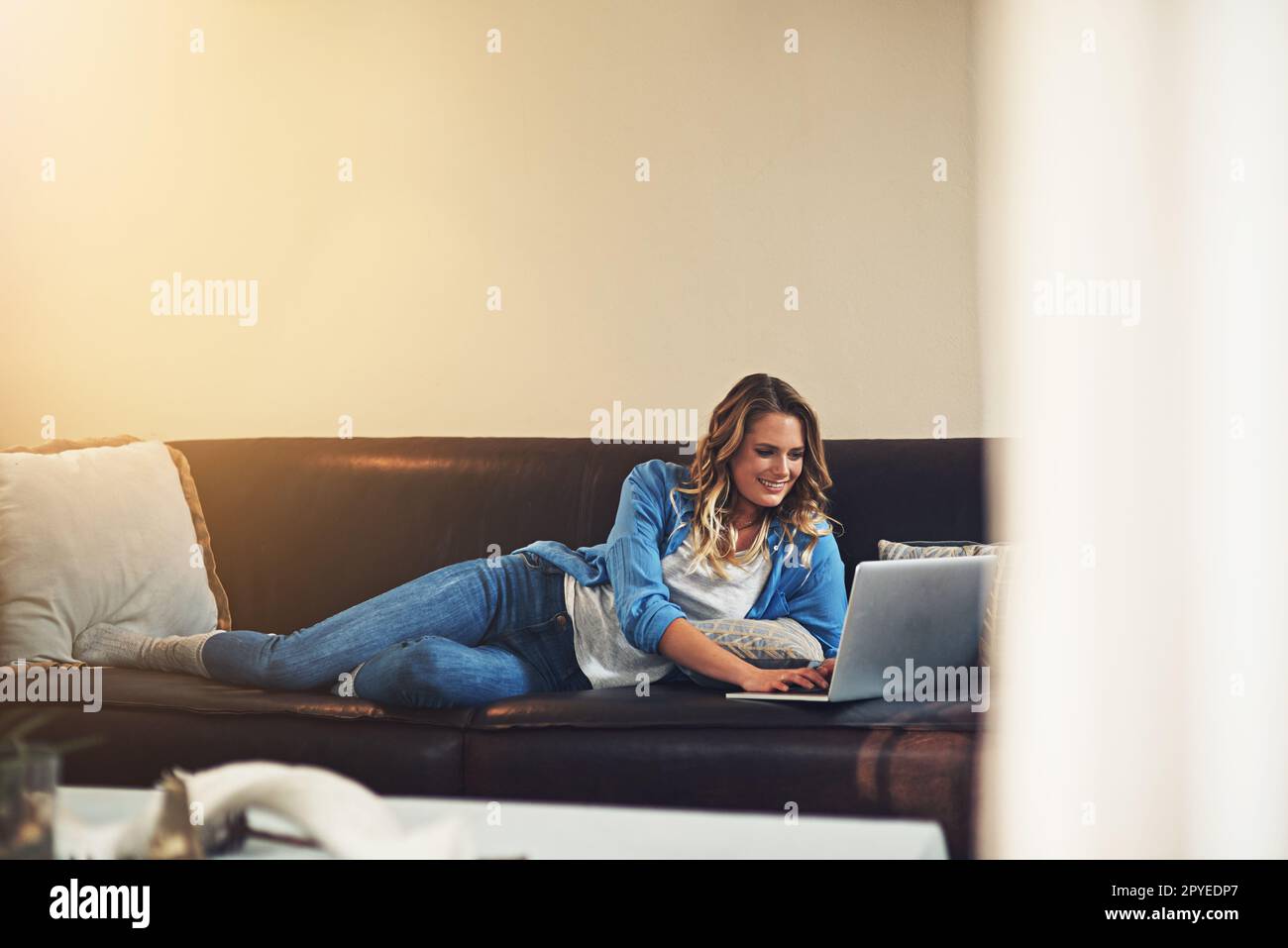 La vie est tellement plus facile quand vous vous détendez. une jeune femme détendue utilisant un ordinateur portable sur le canapé à la maison. Banque D'Images