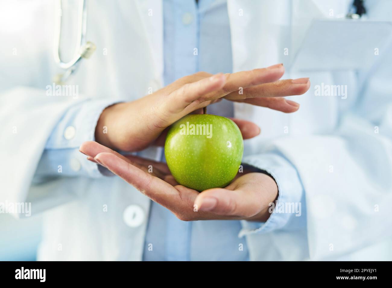 Prenez la santé entre vos mains. Gros plan d'un médecin non identifiable tenant une pomme. Banque D'Images