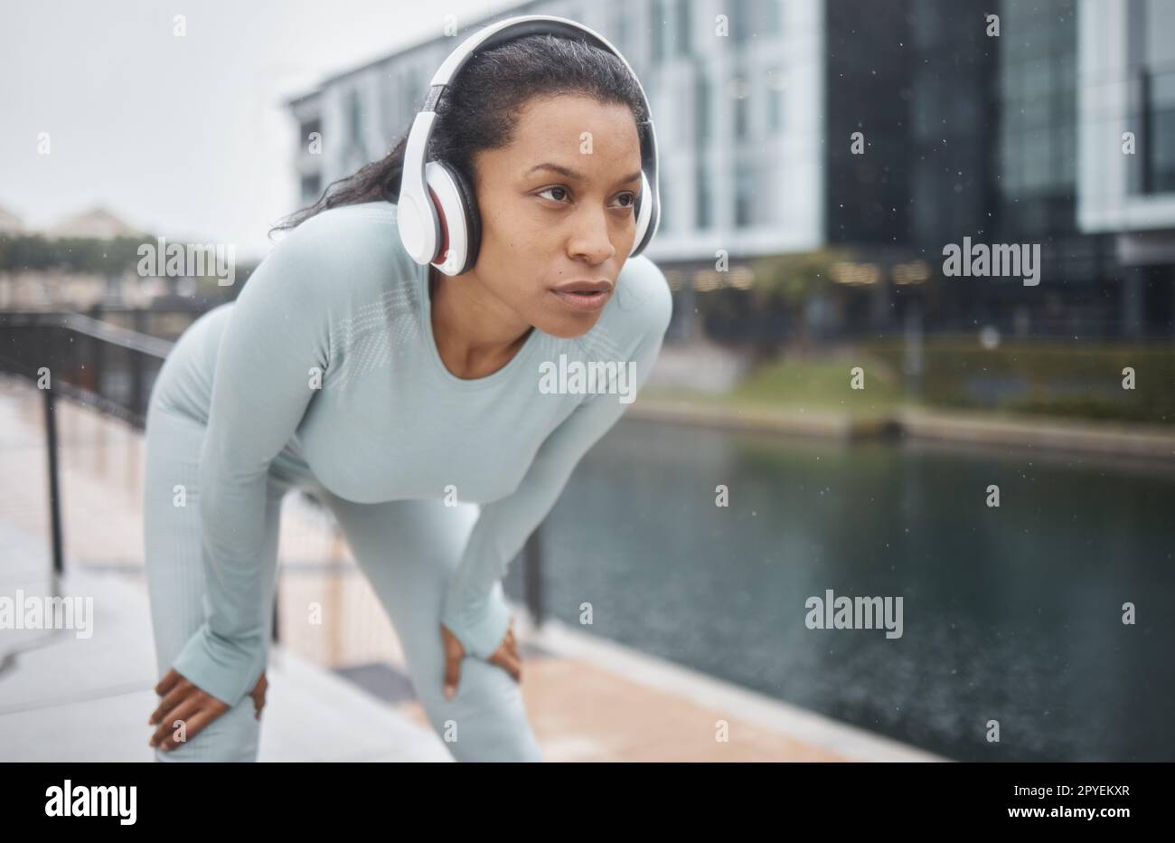 Casque, fitness et coureuse femme dans une rue urbaine avec motivation, musique et exercice. Course en ville, sport et entraînement marathon d'une athlète noire écoutant la radio web pour le sport Banque D'Images