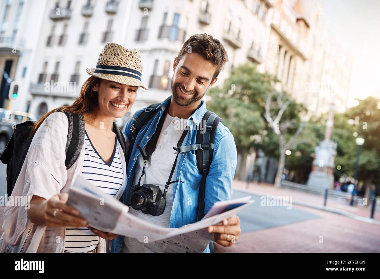Regardons ici... un jeune couple affectueux qui utilise une carte tout en explorant une ville étrangère. Banque D'Images