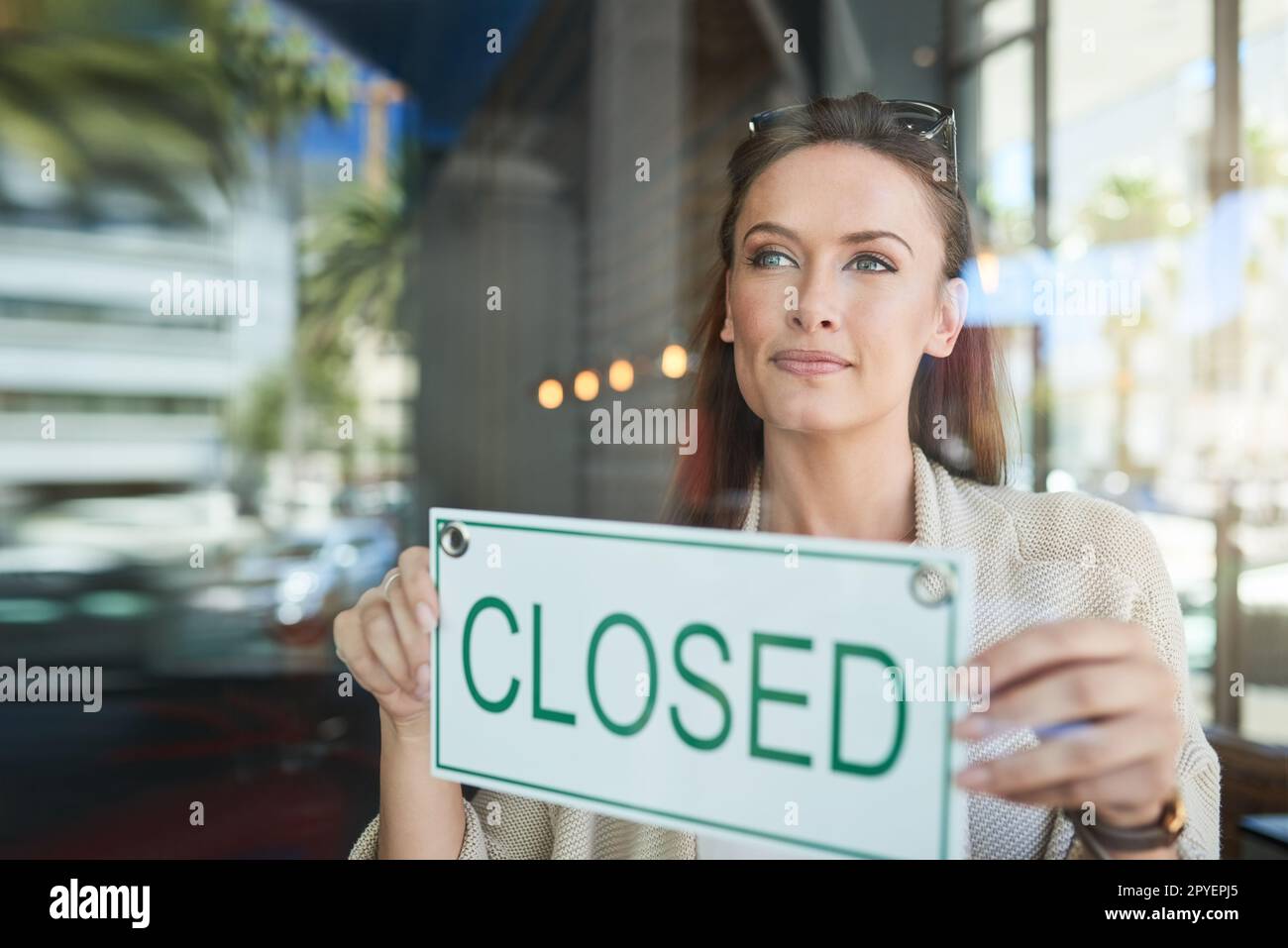 Son heure de fermeture. une jeune entrepreneur tenant un panneau fermé dans son entreprise. Banque D'Images