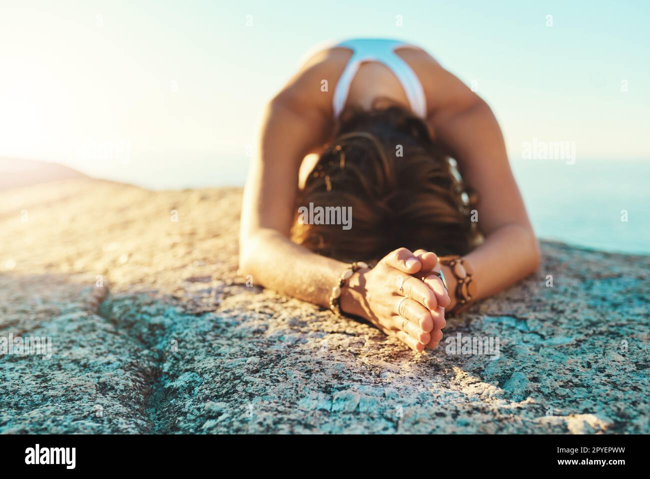 S'incliner vers les dieux. une jeune femme faisant du yoga à la plage. Banque D'Images